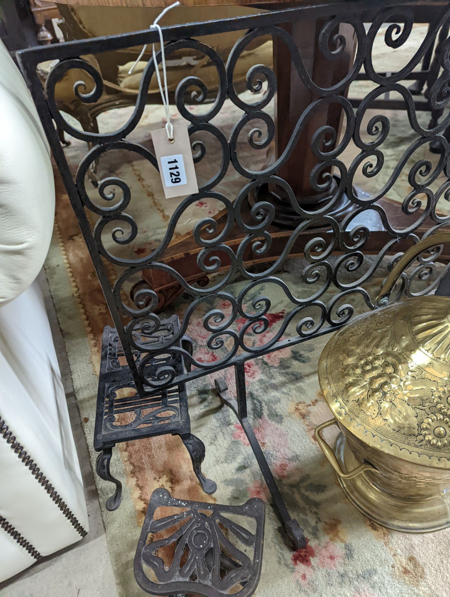 A wrought iron scroll work firescreen, width 95cm, a Dutch embossed brass scuttle, two trivets, coal bin and assorted metalware